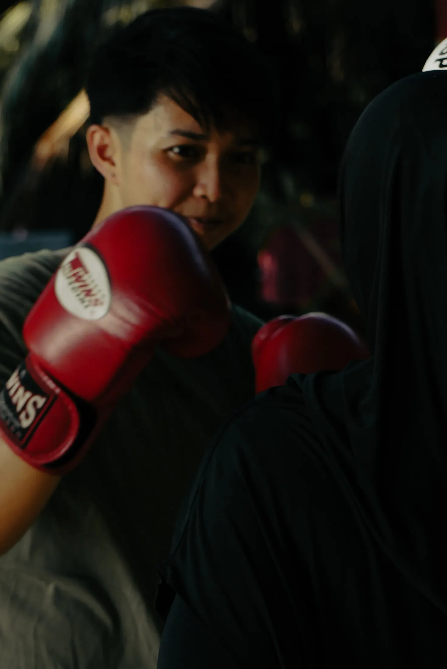 A boxer looks past raised red gloves during practice