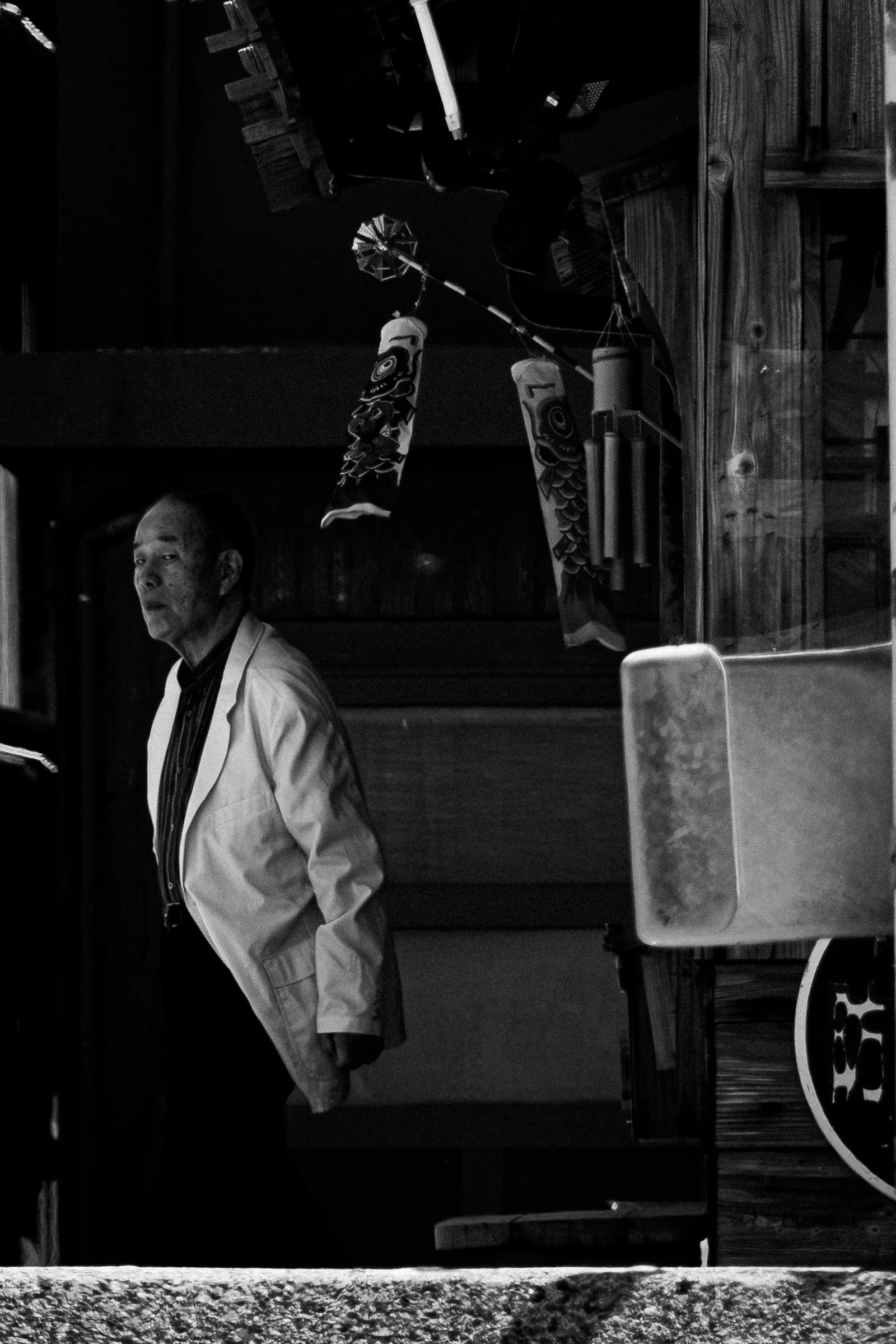 An older man stands at the edge of a dark doorway
