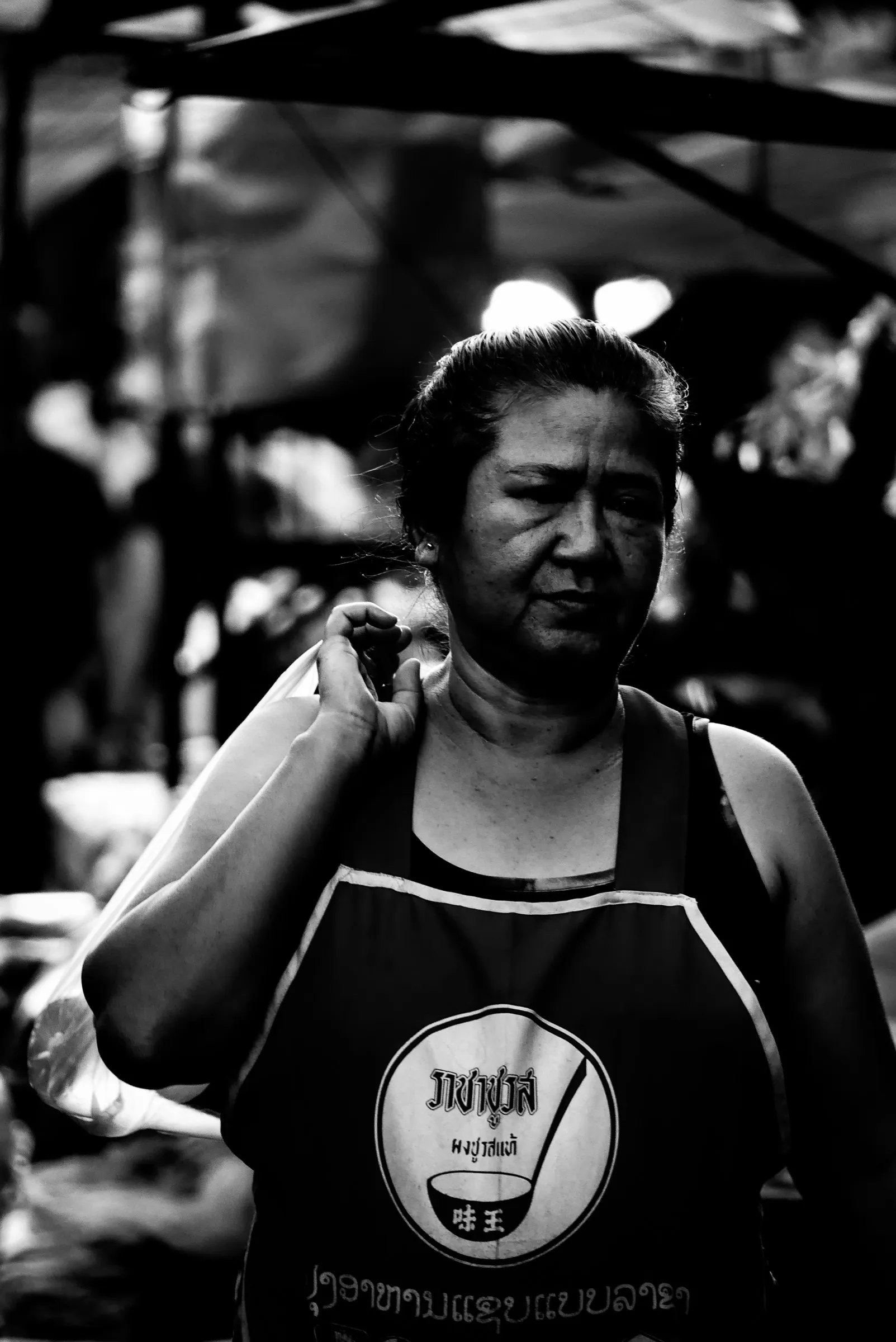A market worker pauses with one hand at her shoulder