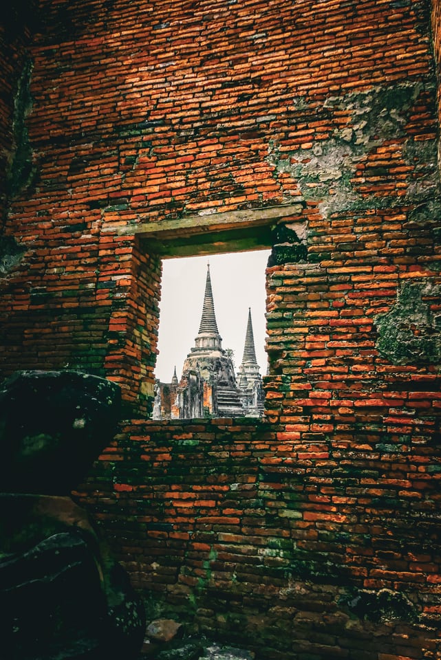 A brick window frames white temple spires beyond.