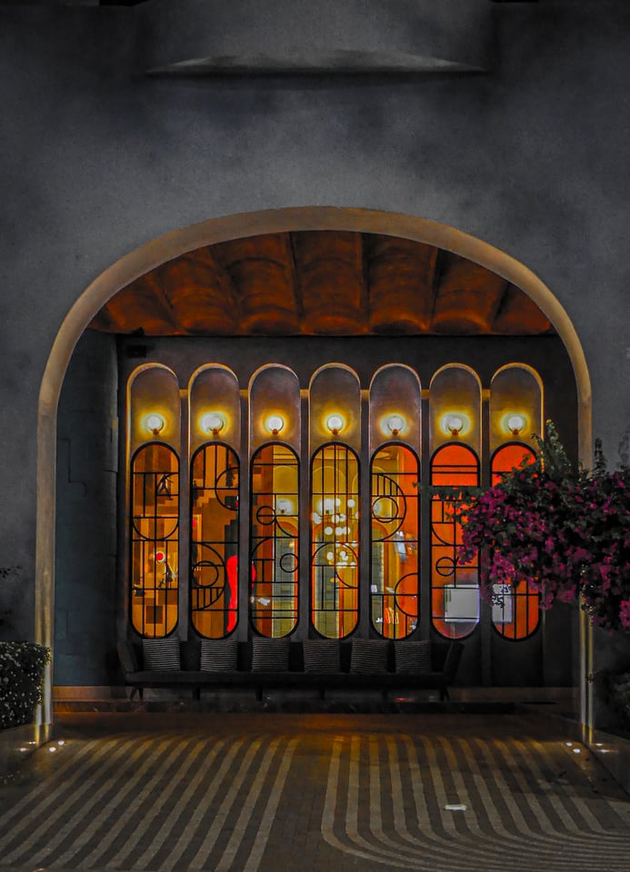 An arcade of coloured glass panels glows inside a stone arch.
