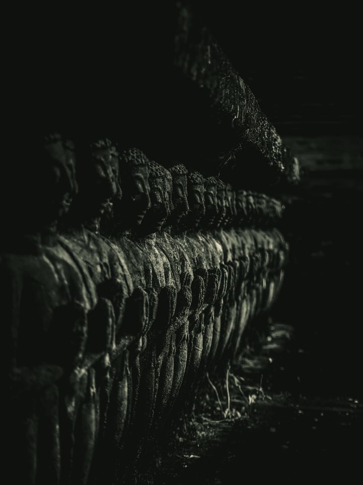 A line of carved figures recedes into darkness along a wall.