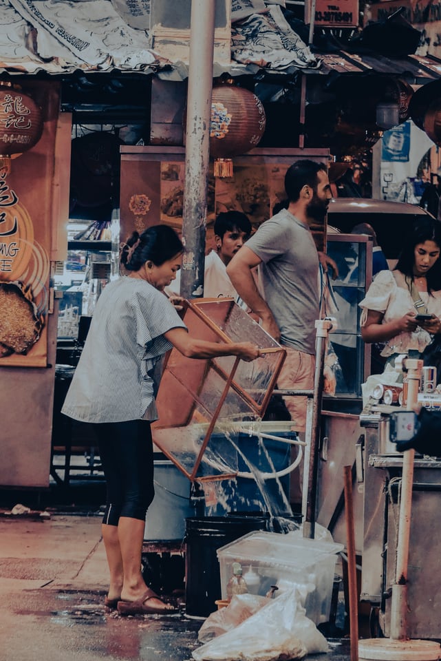 A woman carries a metal frame through a busy market street.
