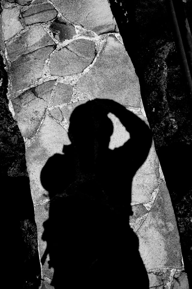 The photographer's shadow falls across cracked stone paving.