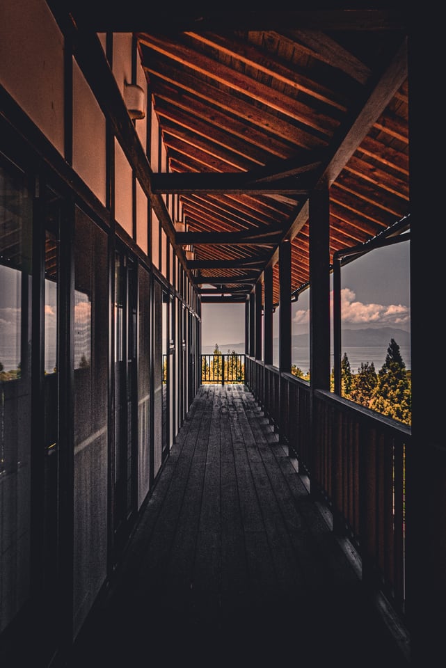 A long wooden corridor opens onto light at its far end.