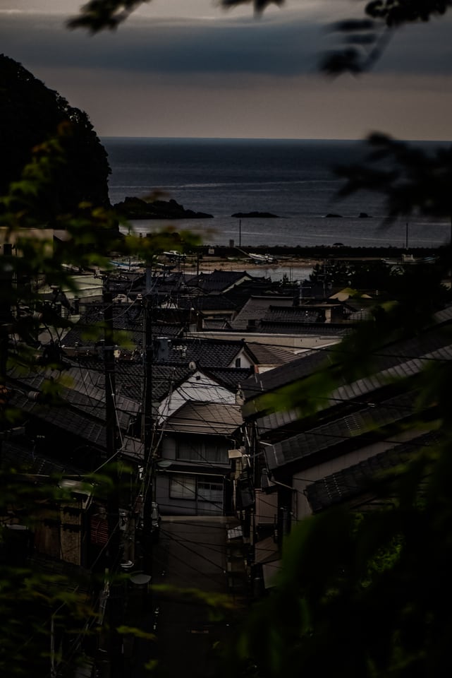 The tiled roofs of a small village stand stacked above a dark sea horizon.