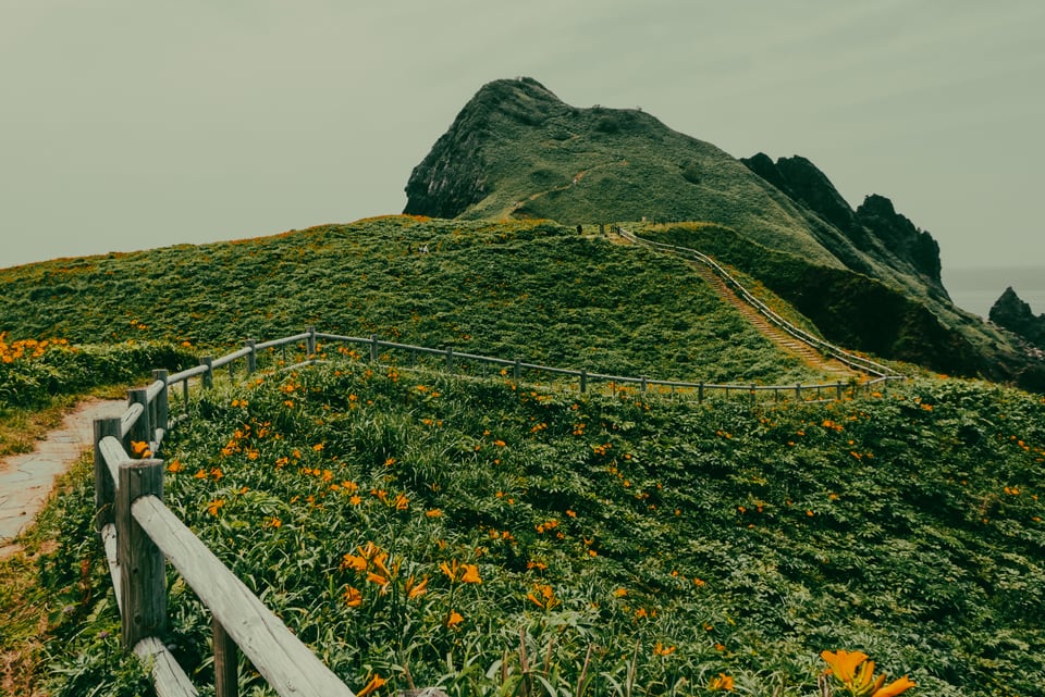 A footpath runs along a green ridge above the sea.