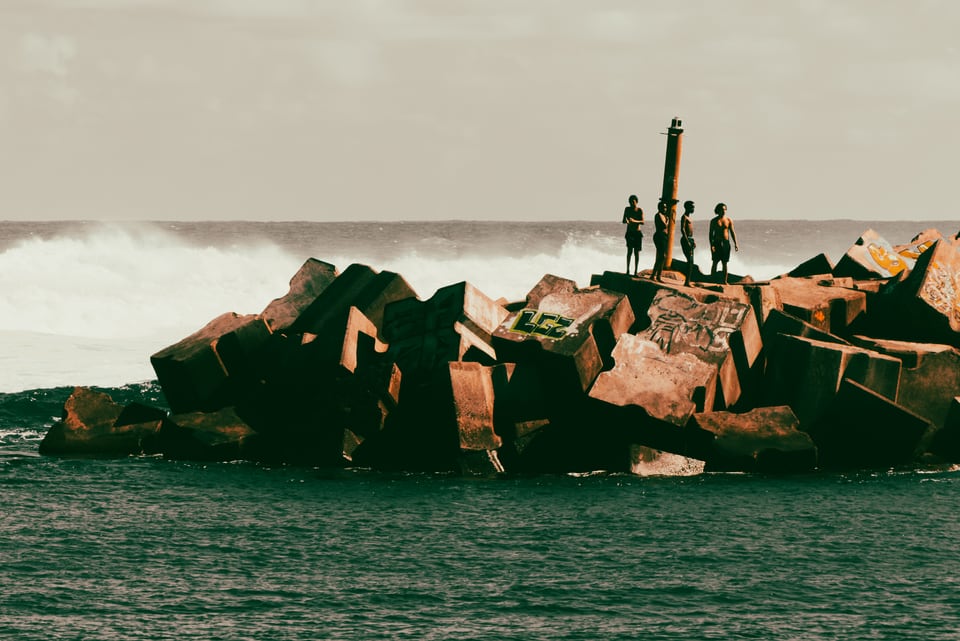 Small figures stand on concrete blocks in a green sea.