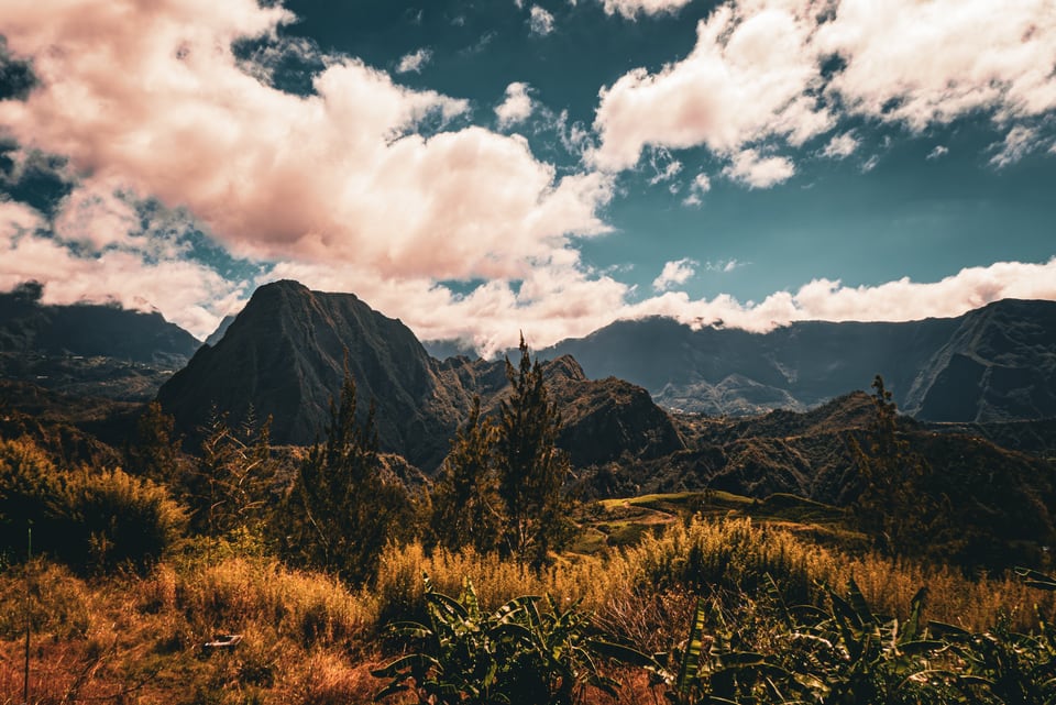 A sharp peak stands among ridges under piled cloud.
