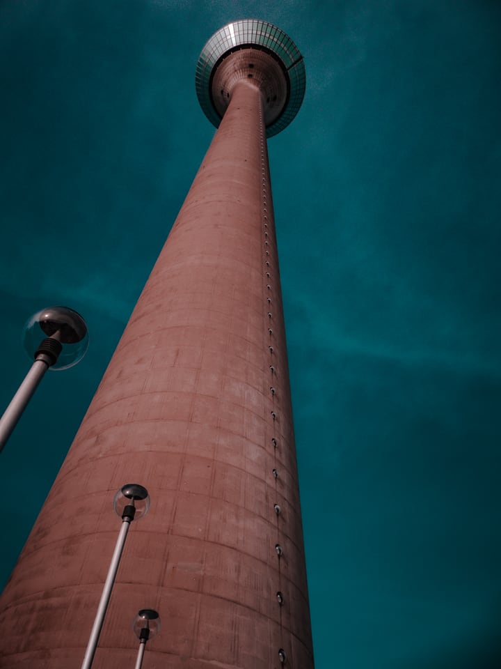 A concrete tower shaft rises into a deep teal sky.